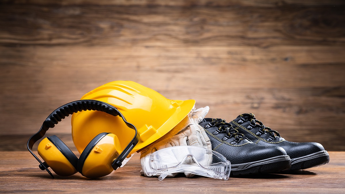 Essential safety equipment including yellow hard hat, ear protection, safety goggles, work gloves, and safety boots